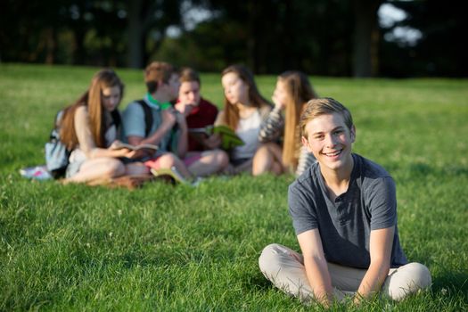Cheeful smiling teen male near group outdoors