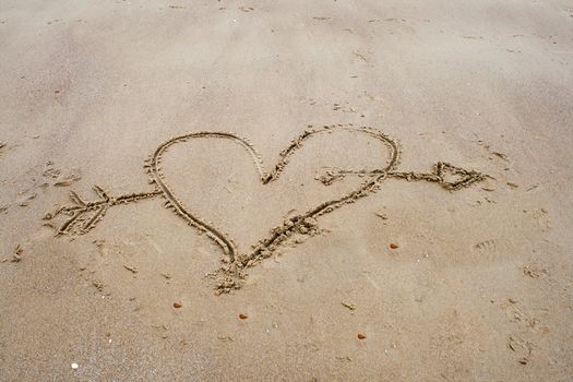 drawing a heart in the sand on beach