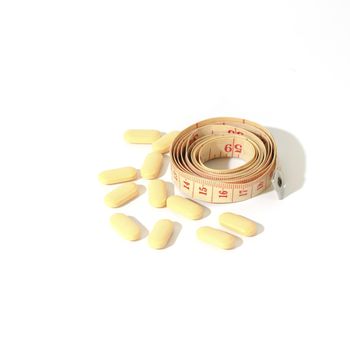 pills and measuring tape on a white background