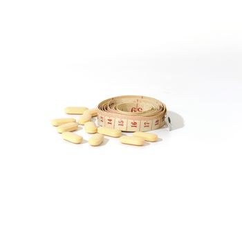 pills and measuring tape on a white background