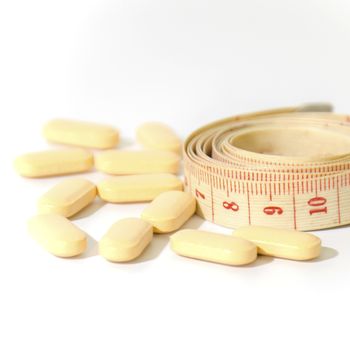 pills and measuring tape on a white background