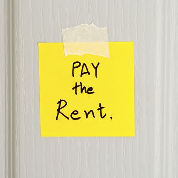sticky note write a message pay the rent on wood door background