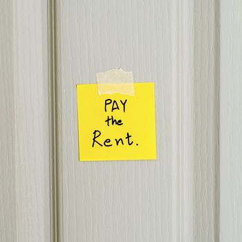 sticky note write a message pay the rent on wood door background