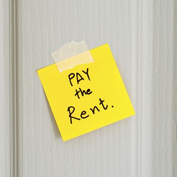 sticky note write a message pay the rent on wood door background