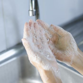Washing of hands with soap on sink