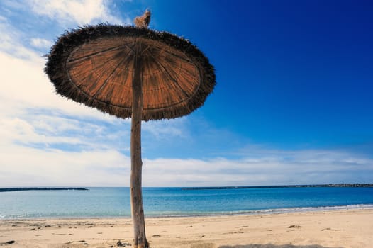 Straw parasol on the sandy tropical beach