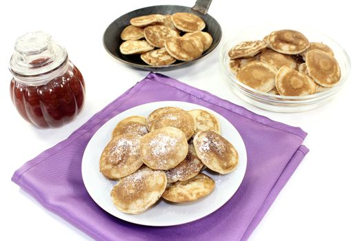 Poffertjes with powdered sugar and fruit jelly on light background