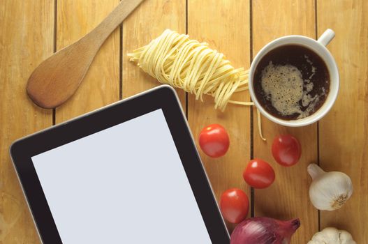 Tablet with copyspace surrounded by fresh food ingredients