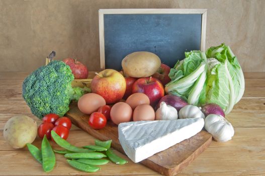 Fresh organic produce including fruits and vegetables with a blank blackboard 