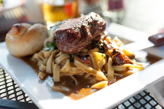 Petite filet mignon on a bed of homemage pasta with mushrooms and truffle oil.  Shallow depth of field. 