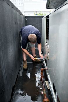 An HVAC heating ventilating air conditioning technician repairing or maintaining a large commercial unit.