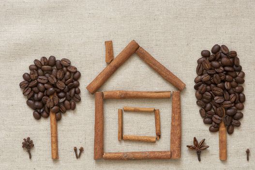 House made of cinnamon sticks and coffee beans with cinnamon and coffee trees