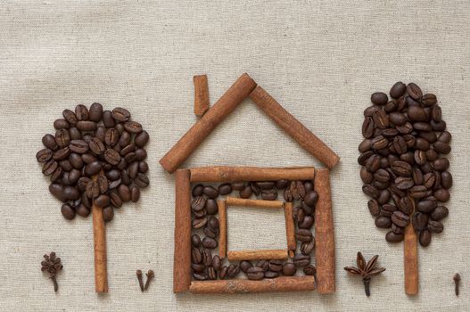 House made of cinnamon sticks and coffee beans with cinnamon and coffee trees