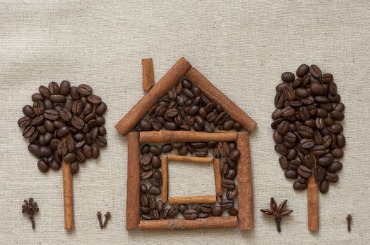 House made of cinnamon sticks and coffee beans with cinnamon and coffee trees