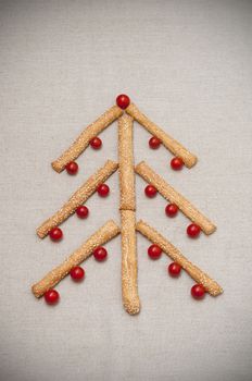 Christmas card, tree made of grissini and cherry tomatoes on linen fabric