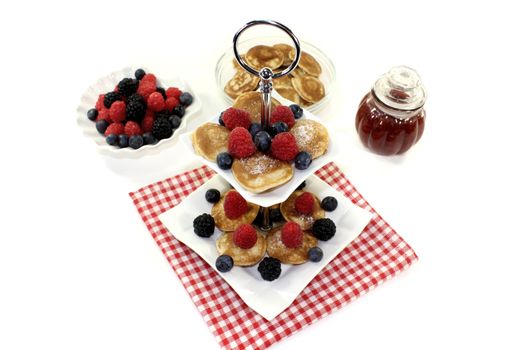 Poffertjes with raspberries on a cake stand on a light background