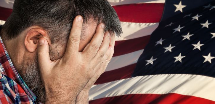 Veteran. Portrait of an elderly man with face closed by hand on USA flag background. 