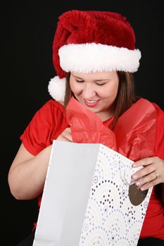 Beautiful caucasian brunette looking inside her christmas gift bag 