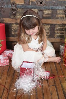 Little girl wearing a christmas dress looking at gifts 