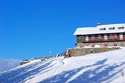 Winter mountain chalet and the blue sky behind