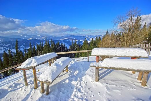 A lot of snow on tables and seats.