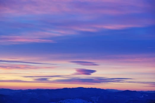 Colored clouds at sunrise over the mountains.
