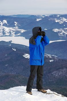Man searching with binocular on mountain.