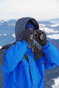 Tourist on mountain looking through binocular.