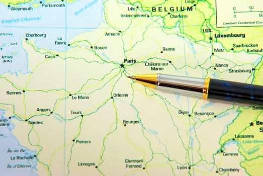 Pen indicating Paris city on France map.