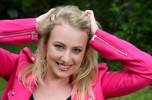 Beautiful smiling young blond woman in a pink jacket