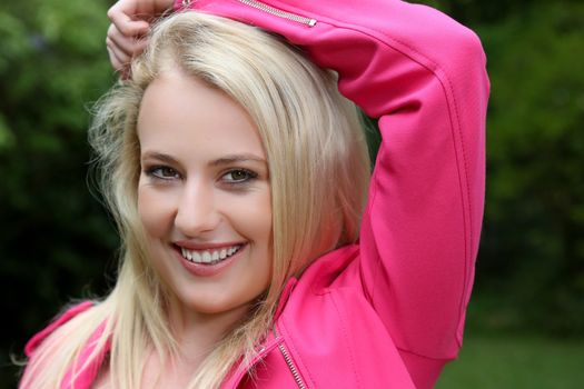 Beautiful smiling young blond woman in a pink jacket