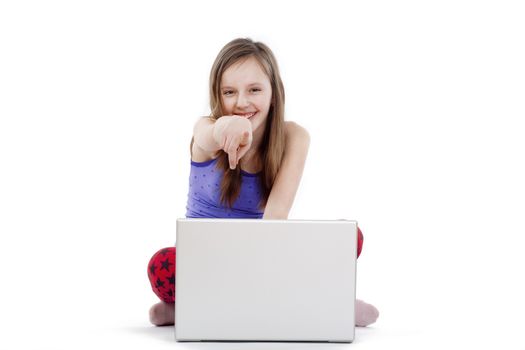 girl sitting on the floor with laptop pointing at camera smiling