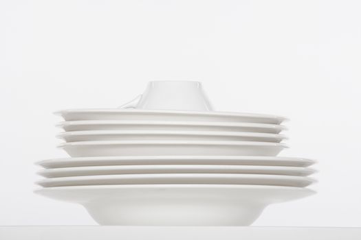 studio shot of a pile of white plates and white cup isolated on white