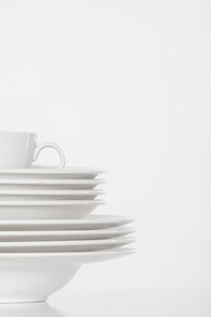 studio shot of a pile of white plates and white cup isolated on white