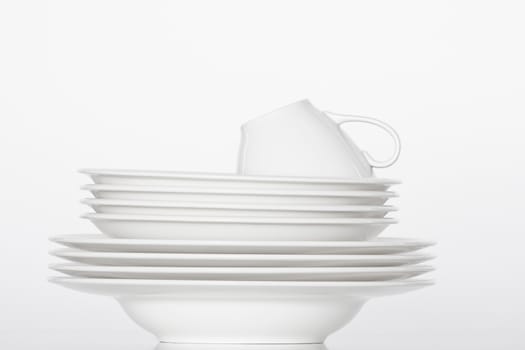 studio shot of a pile of white plates and white cup isolated on white