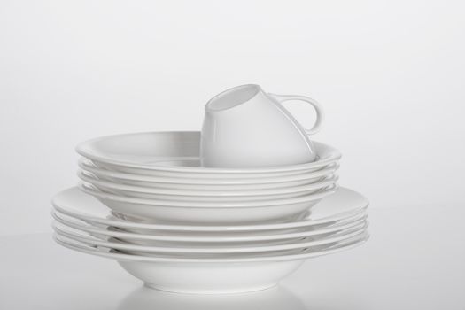 studio shot of a pile of white plate and white cup isolated on white