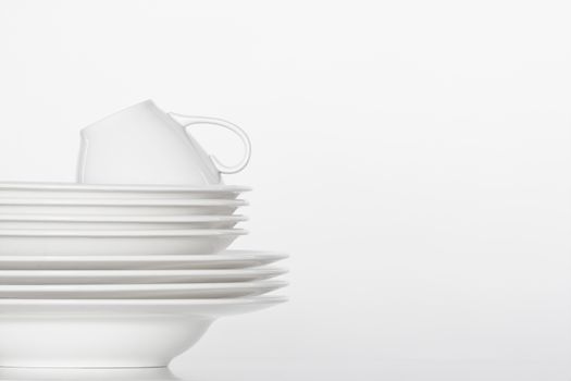 studio shot of a pile of white plate and white cup isolated on white