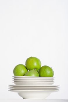 studio shot of a pile of plates and green apples isolated on white