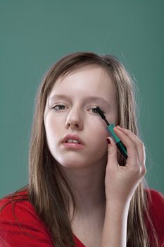 portrait of a pretty eleven years old girl putting on makeup