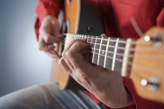 closeup of hands of a musician playing acoustic guitar