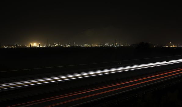 Car trails with an industrial plant on the background