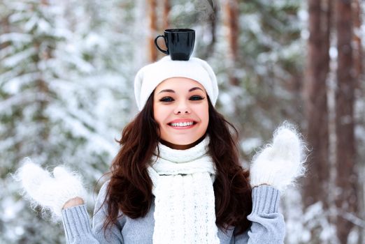 Happy woman with a cup of hot tea on her head