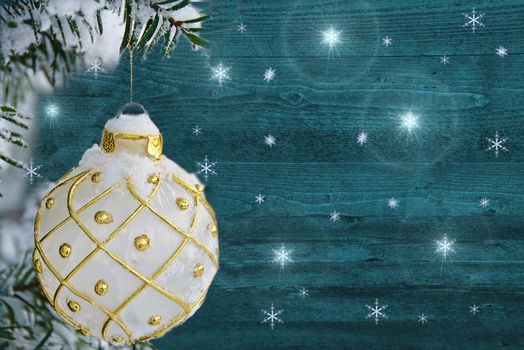 Christmas background with stars, snowflakes against a rustic blue wooden wall and a white Christmas bulb hanging from pine with snow