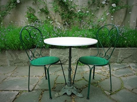Chairs and table in a magic green summer garden.