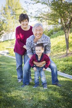 Happy Chinese Grandparents Having Fun with Their Mixed Race Grandson Outside.