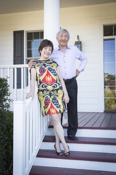 Attractive Happy Chinese Couple Enjoying Their House Outside.