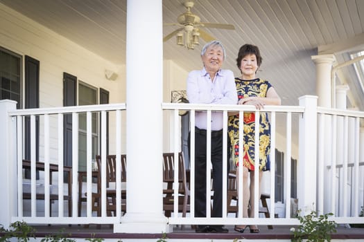 Attractive Happy Chinese Couple Enjoying Their House Outside.