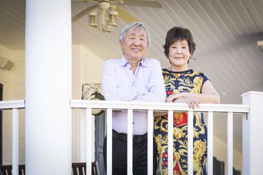 Attractive Happy Chinese Couple Enjoying Their House Outside.