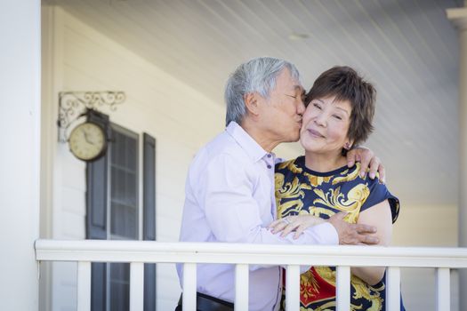 Attractive Happy Chinese Couple Enjoying Their House Outside.