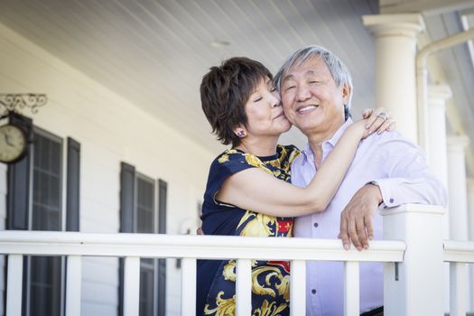 Attractive Happy Chinese Couple Enjoying Their House Outside.